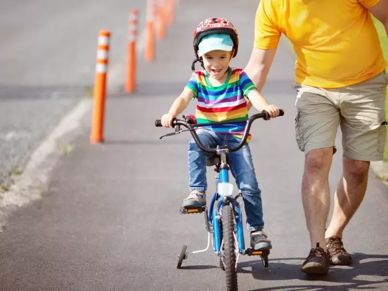 Child on bike with stabilisers training wheels